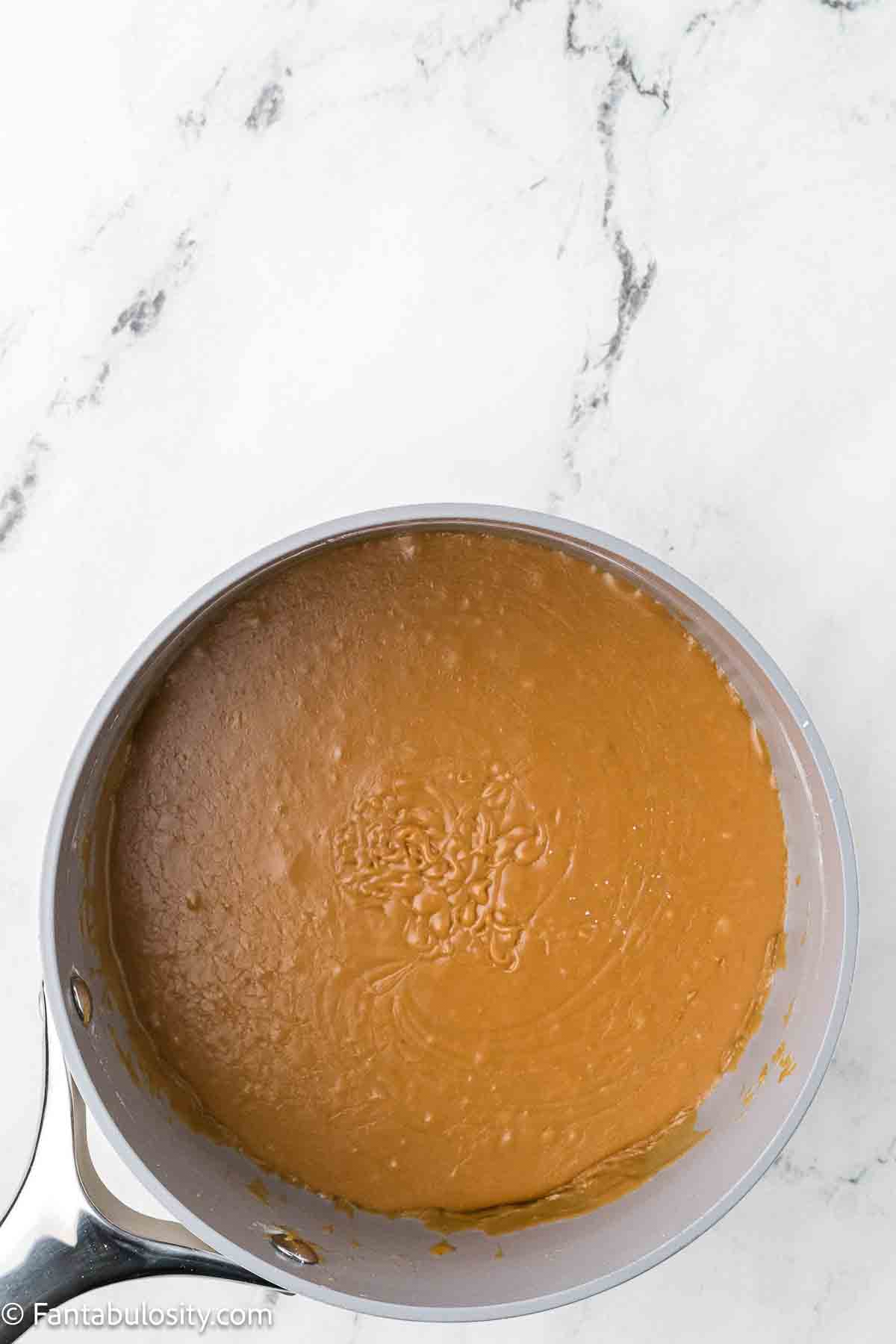 Burnt sugar frosting in sauce pan with powdered sugar added.