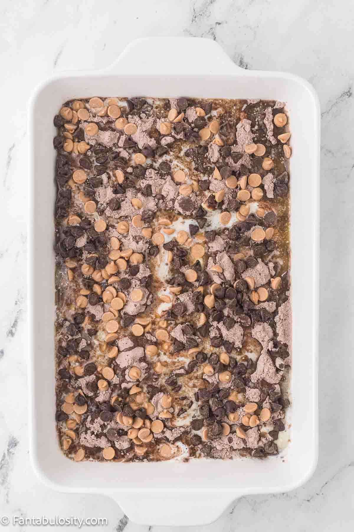Chocolate chips and peanut butter chips on top of cake mix in 9x13 baking pan.