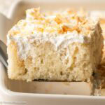A slice of coconut poke cake on a spatula.