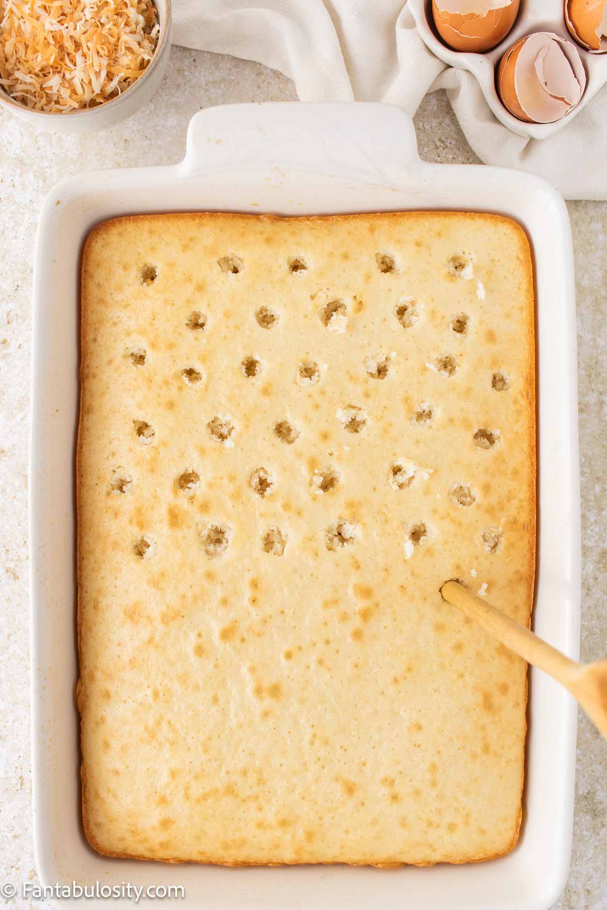 Poking holes in white baked cake.