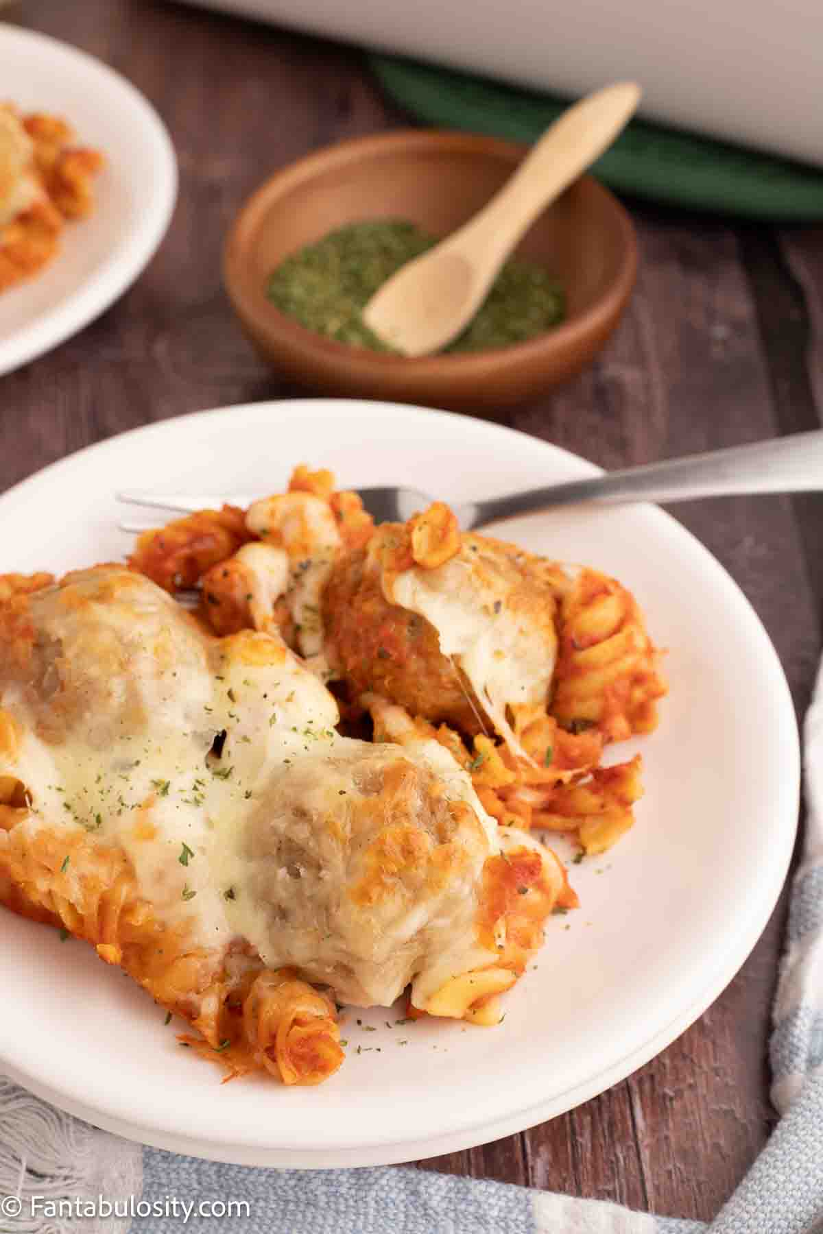 A serving of meatball casserole on a round plate, with a fork.