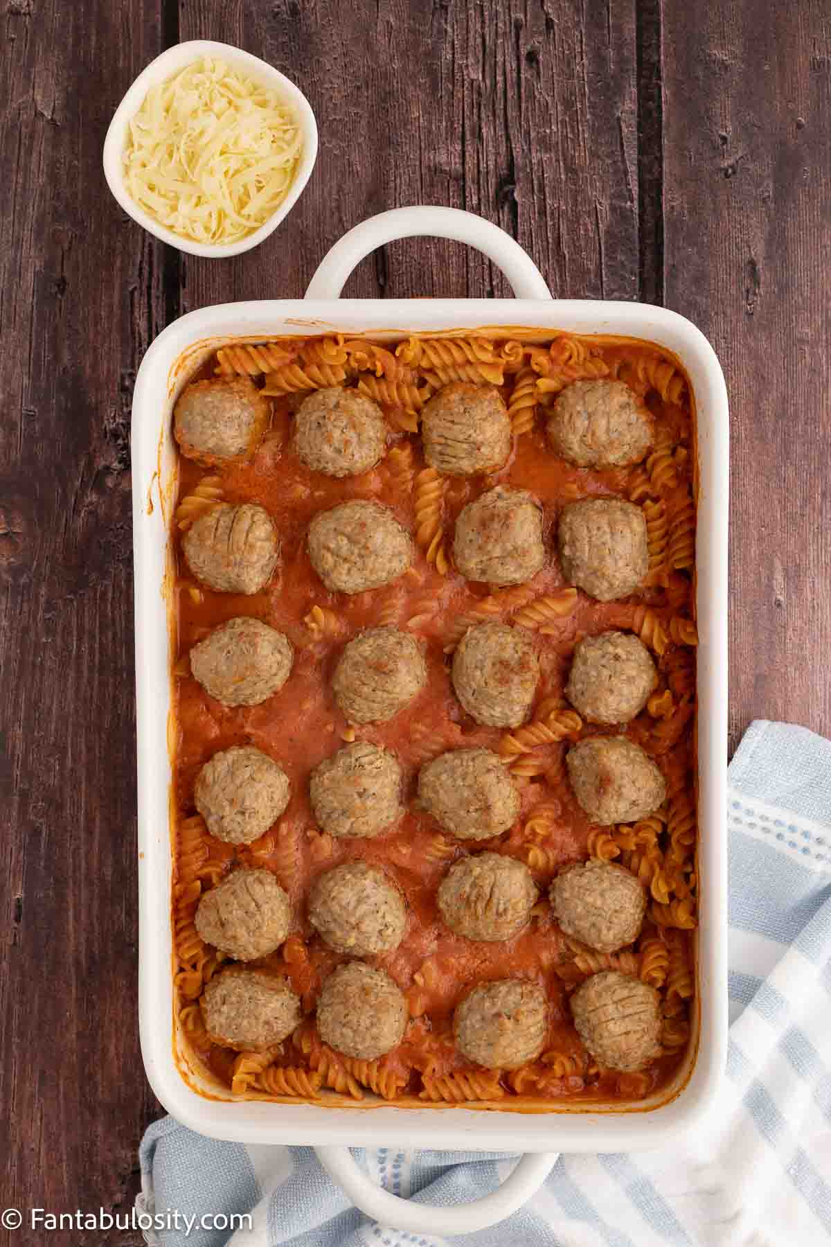 Baked meatballs and cooked pasta in 9x13 baking dish.