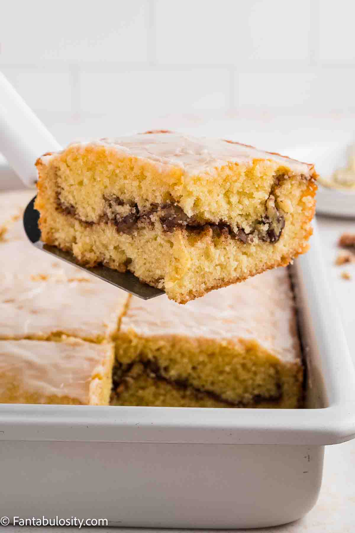 A slice of sock it to me cake on a spatula above rest of cake.
