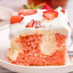 A slice of strawberry cheesecake poke cake on a round plate.