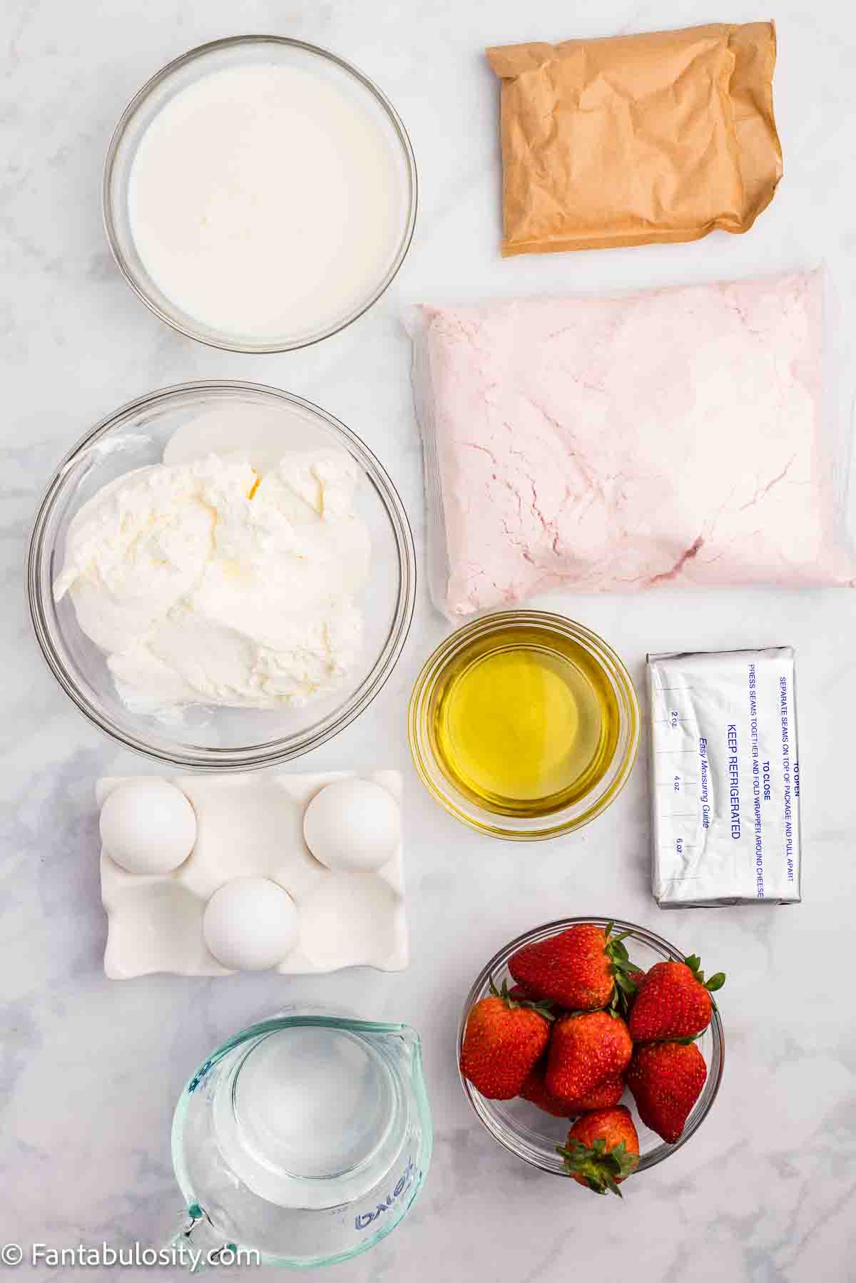 Ingredients to make a strawberry cheesecake poke cake on a kitchen counter.
