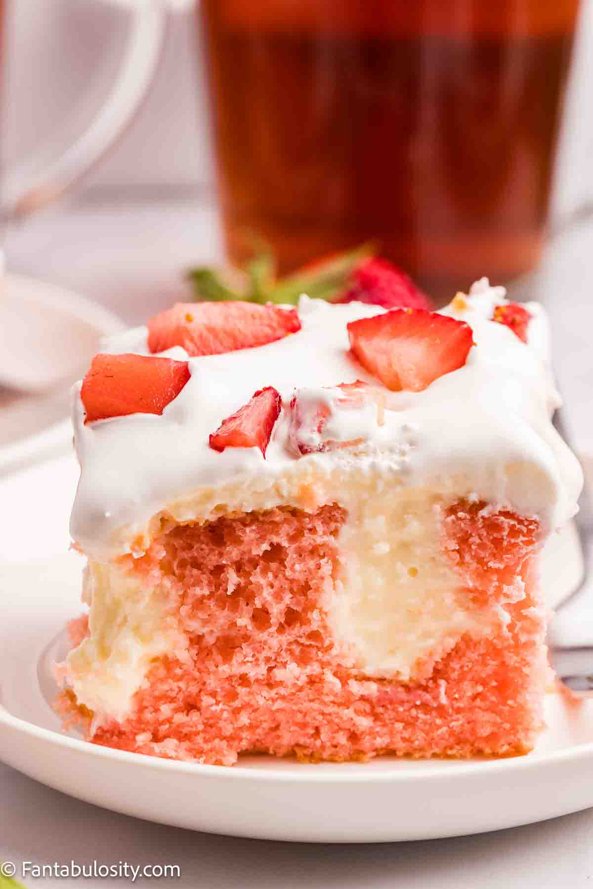 A slice of strawberry cheesecake poke cake on a round plate.