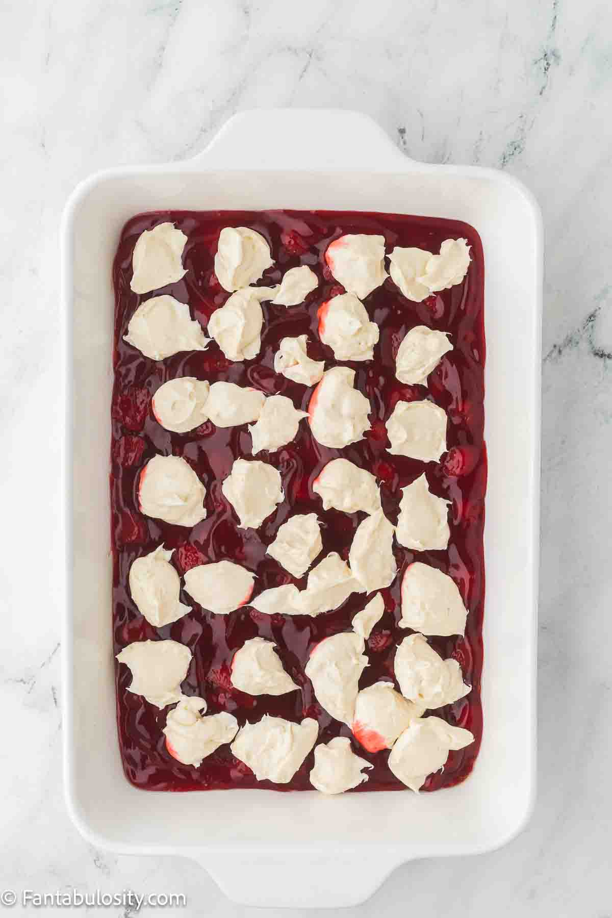 Cream cheese mixture dropped in spoonfuls on top of strawberry pie filling in 9x13 baking dish.
