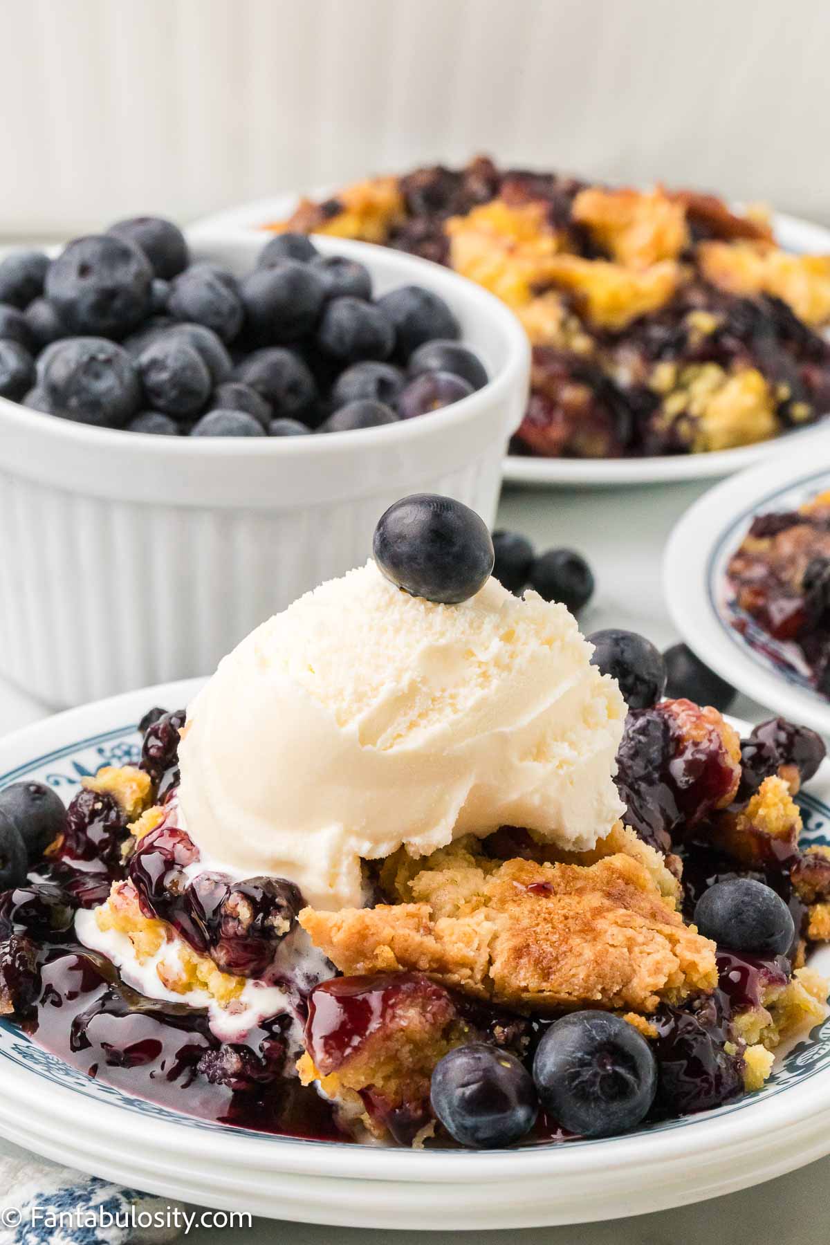 Blueberry dump cake topped with a scoop of vanilla ice cream. 