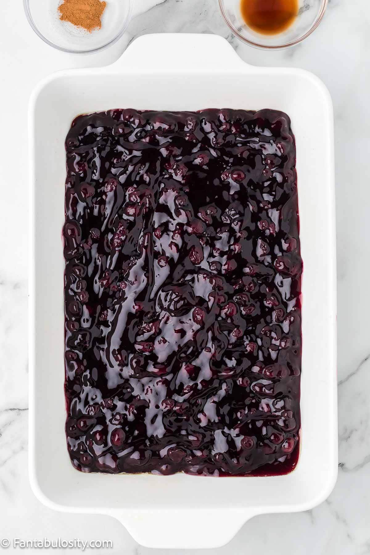 Canned blueberry pie filling spread in bottom of 9x13 baking dish.