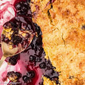 Blueberry dump cake, with serving spoon resting in pan.