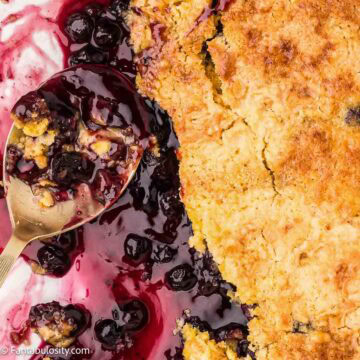 Blueberry dump cake, with serving spoon resting in pan.