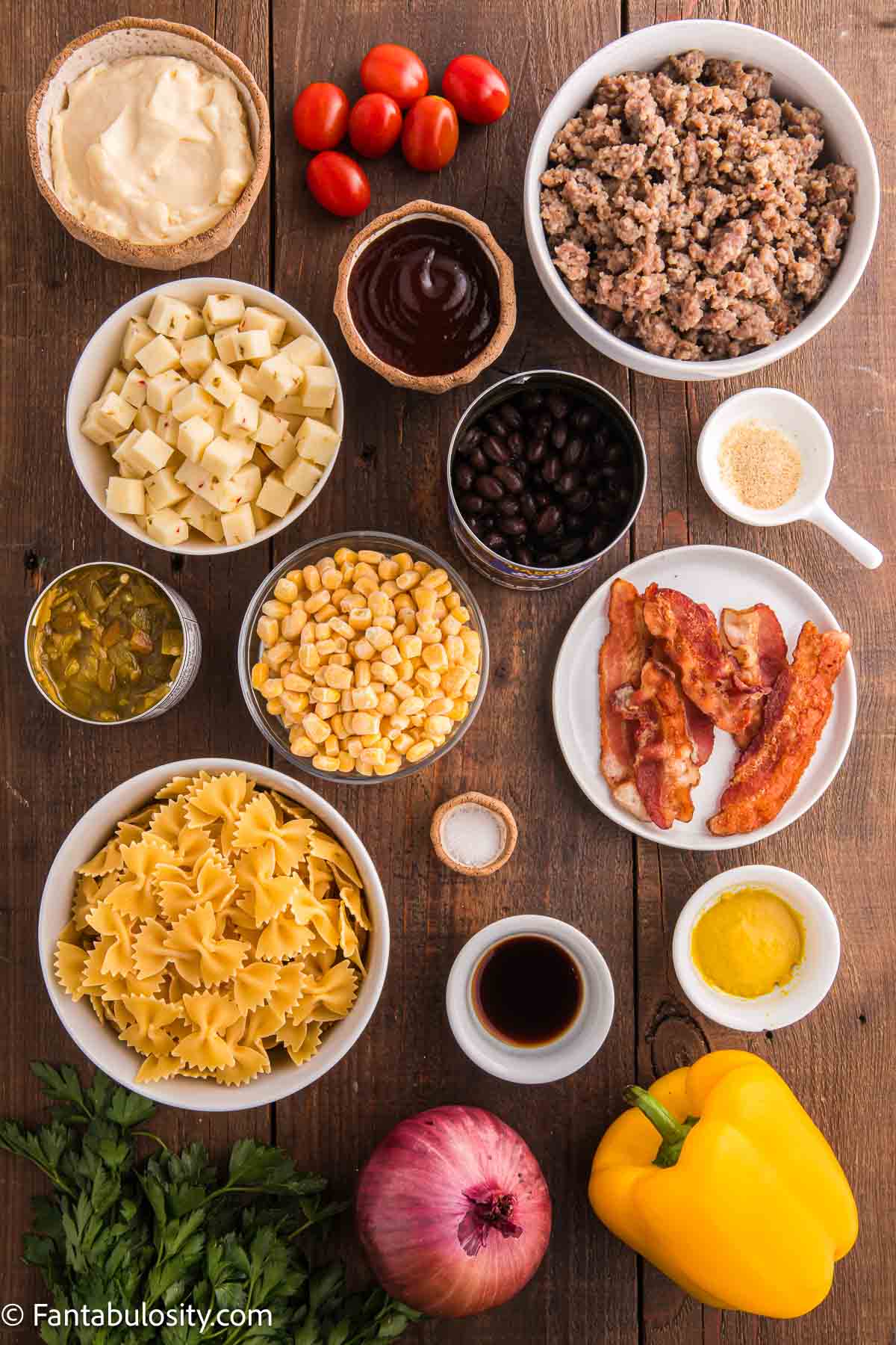 Ingredients to make cowboy pasta salad sitting on wooden table.