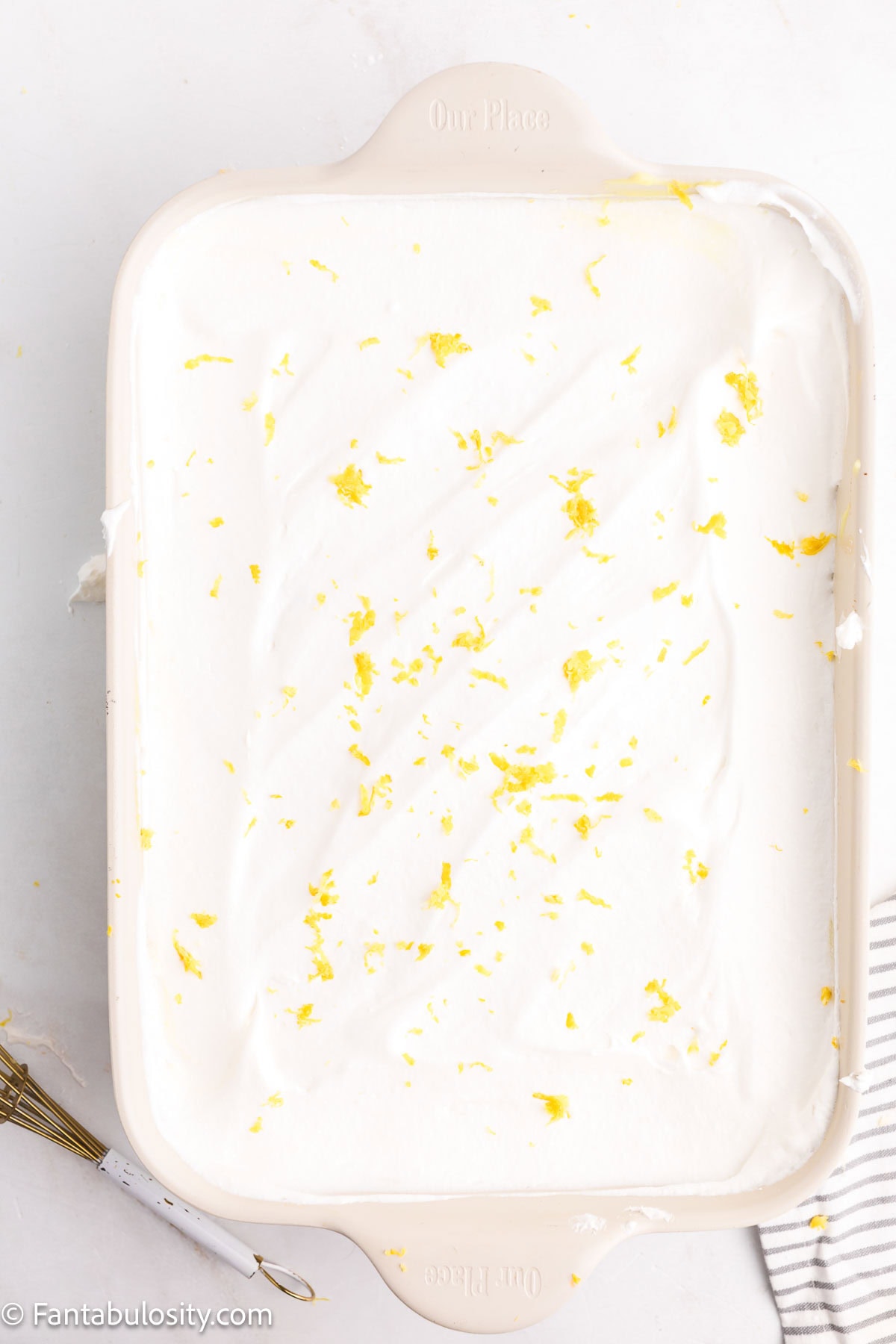 Cool Whip spread on top of lemon layer and lemon zest sprinkled on top for no-bake lemon dessert.