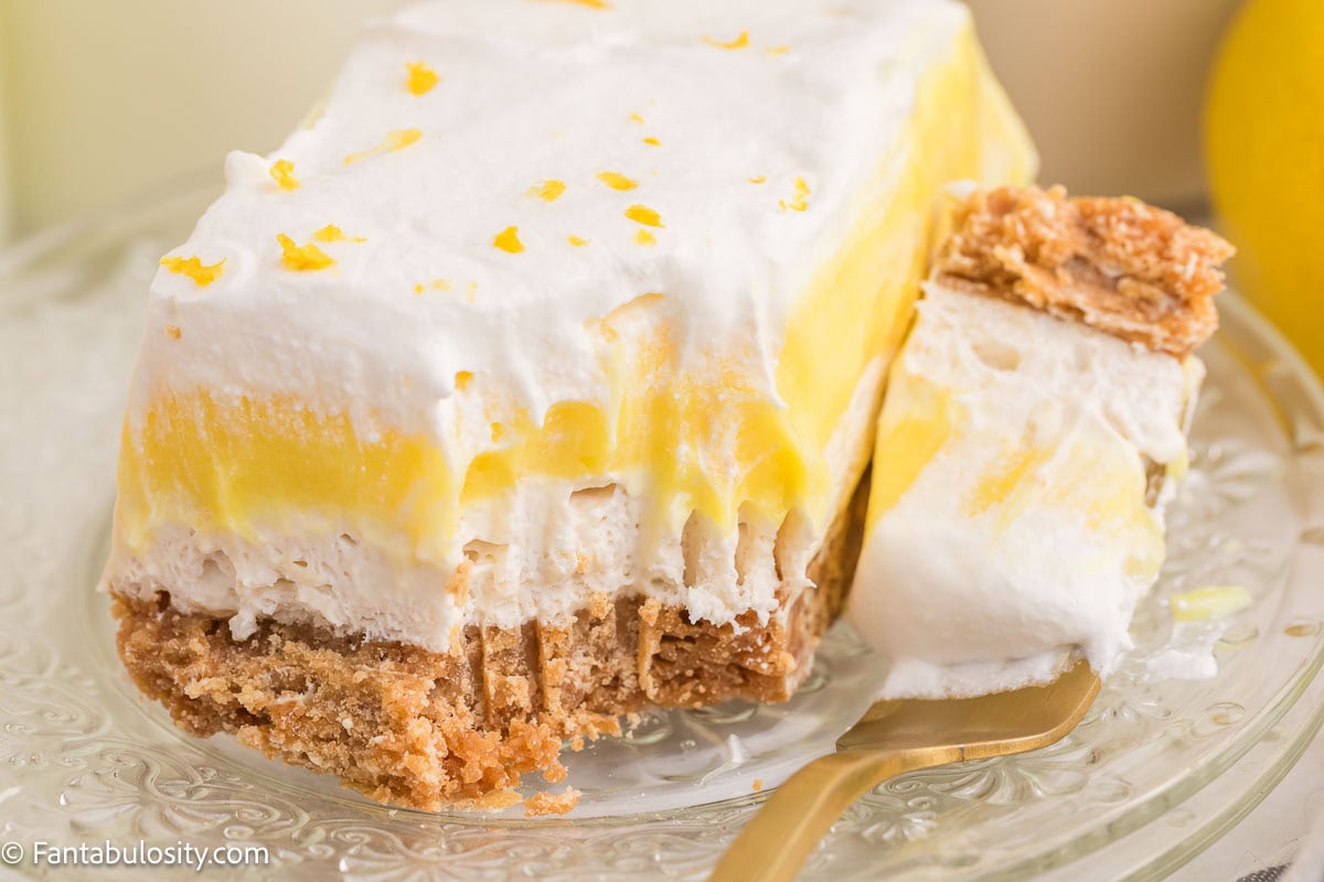 A slice of lemon lush on a plate, with a fork taking a bite off.