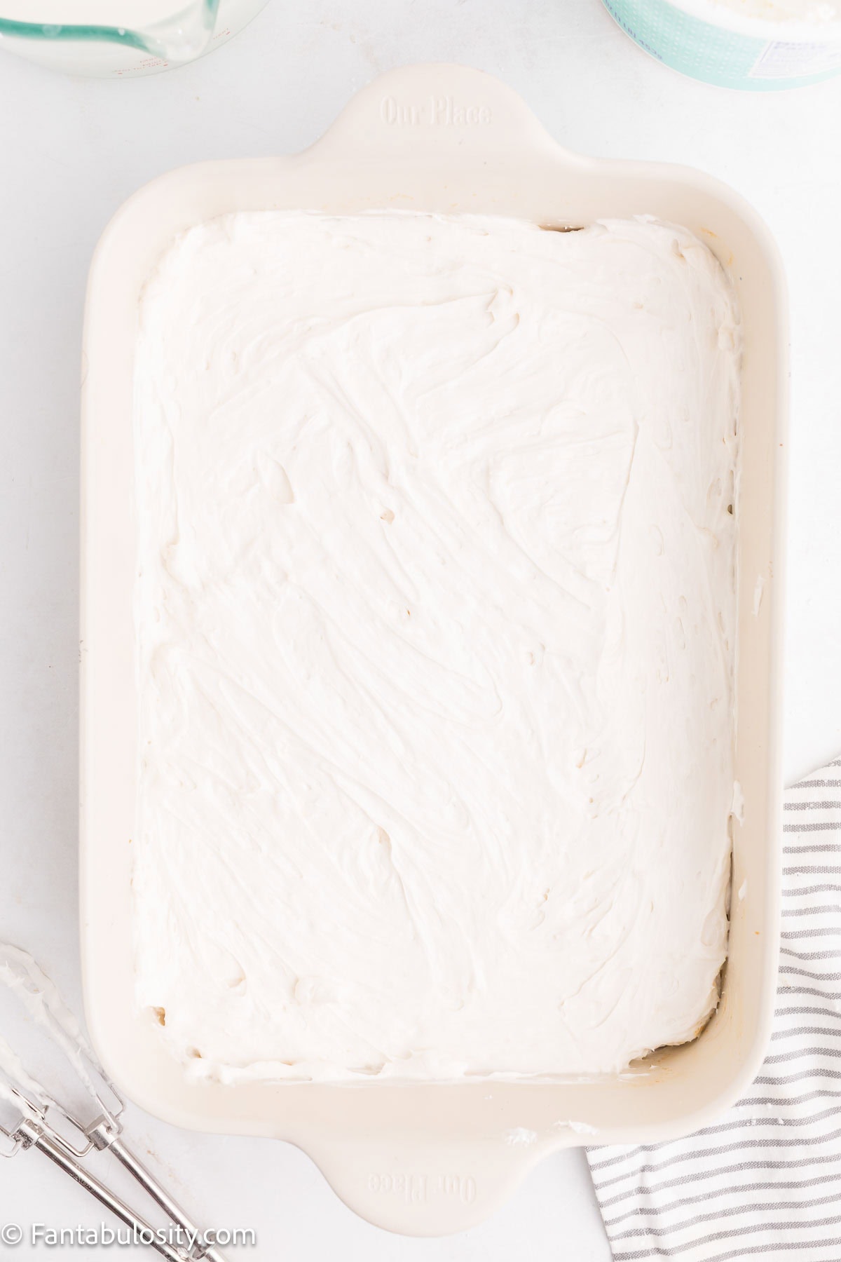 Cream cheese mixture layered on top of graham cracker crust in baking pan for lemon lush.