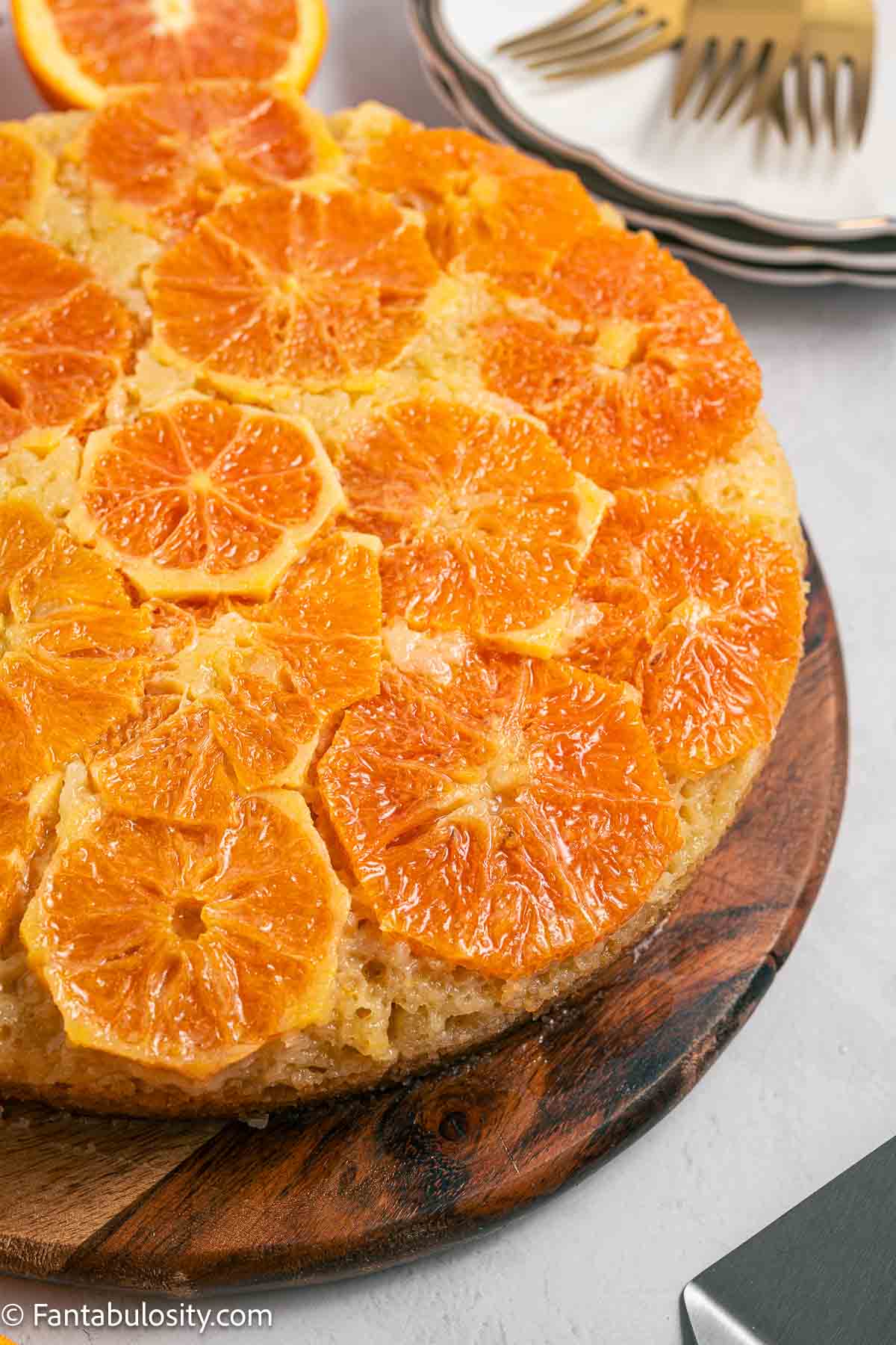A whole orange upside down cake on wooden cutting board.