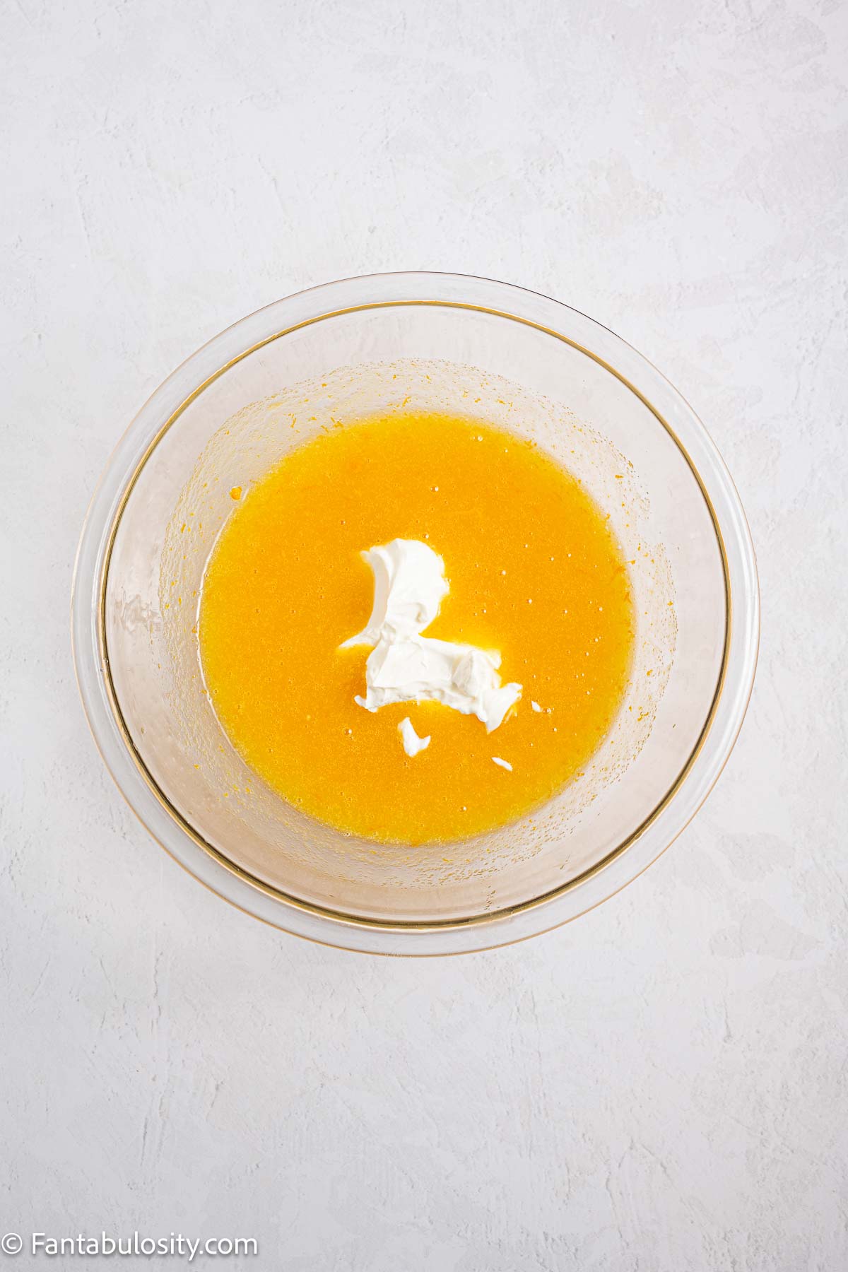 Sour cream added to mixing bowl with orange zest, eggs and sugar.