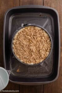 Cheesecake in roasting pan with wrapped springform pan.