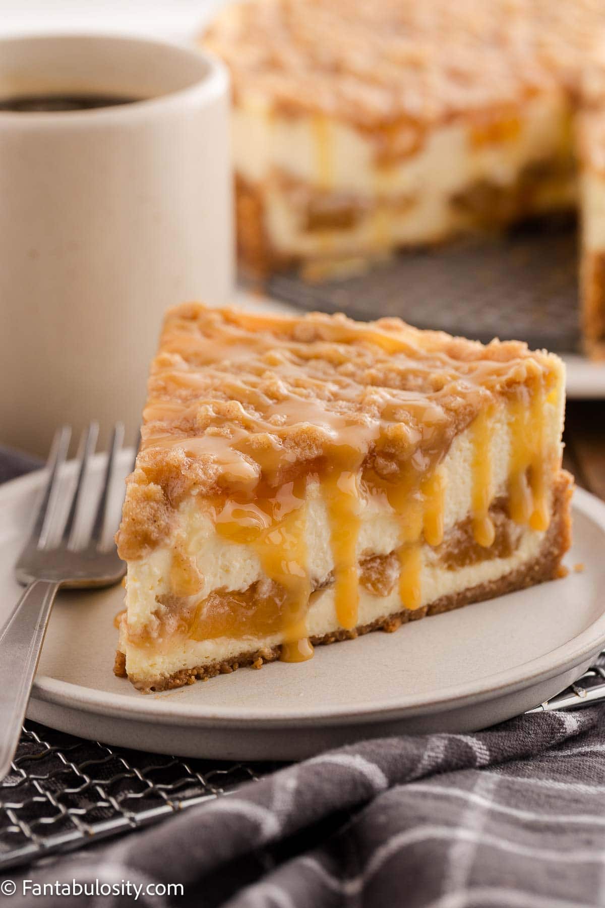 A slice of peach cobbler cheesecake on a plate with fork.
