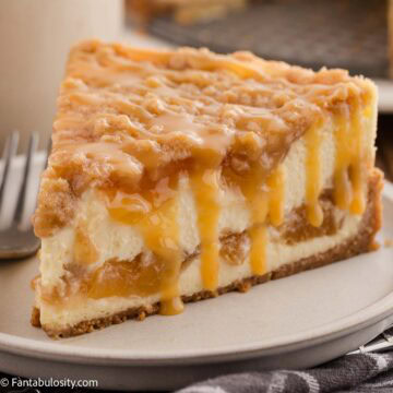 A slice of peach cobbler cheesecake sitting on a plate next to a fork.