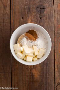 Butter, flour, cinnamon and brown sugar in mixing bowl for cheesecake crumble.