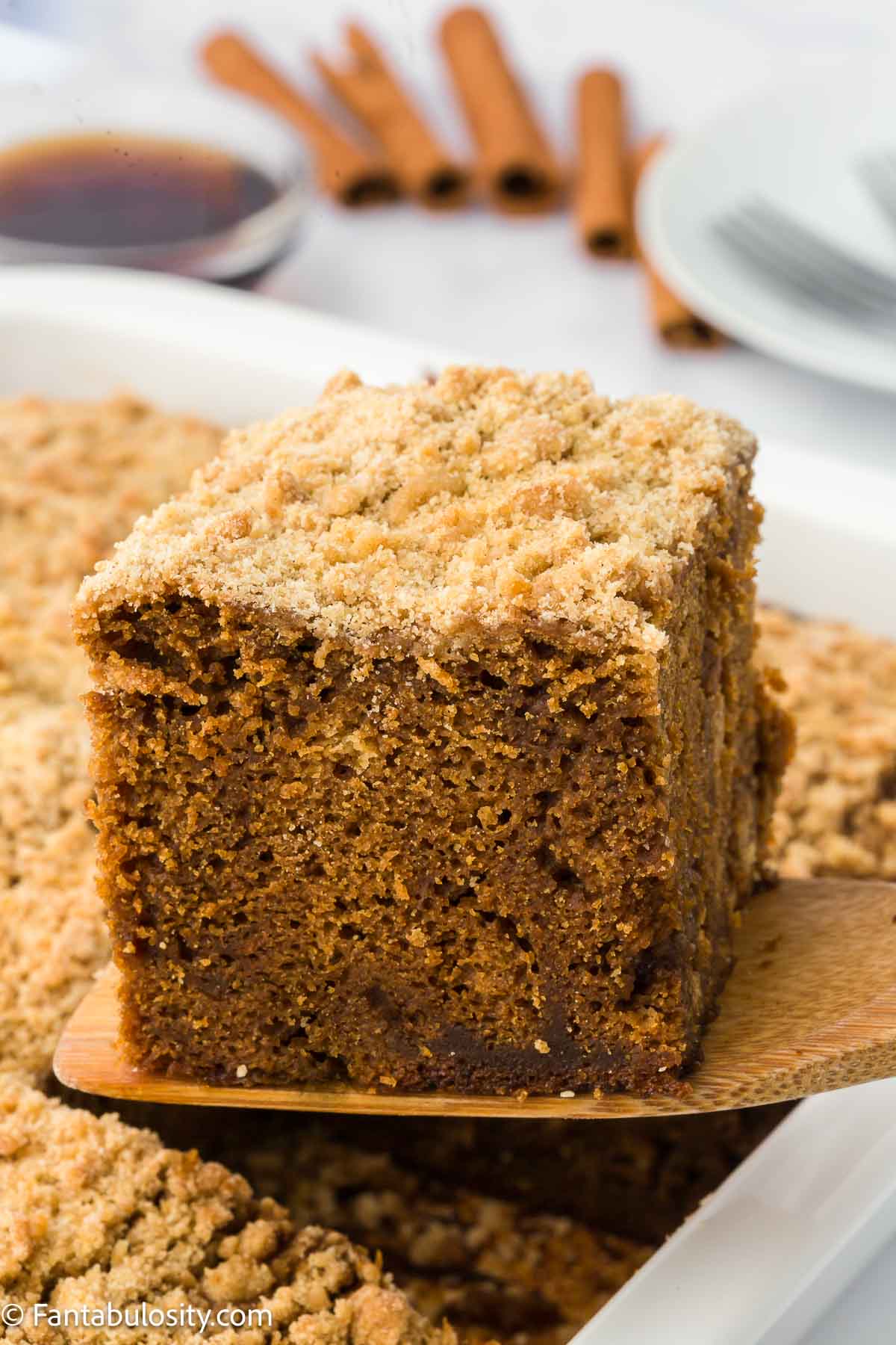 Spatula holding a slice of shoofly cake above pan of cake.