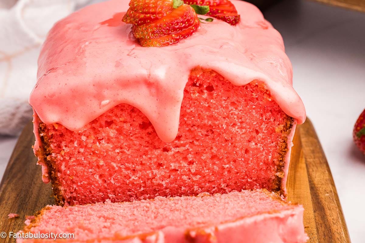 Sliced strawberry bread with strawberry icing, with strawberry topping.