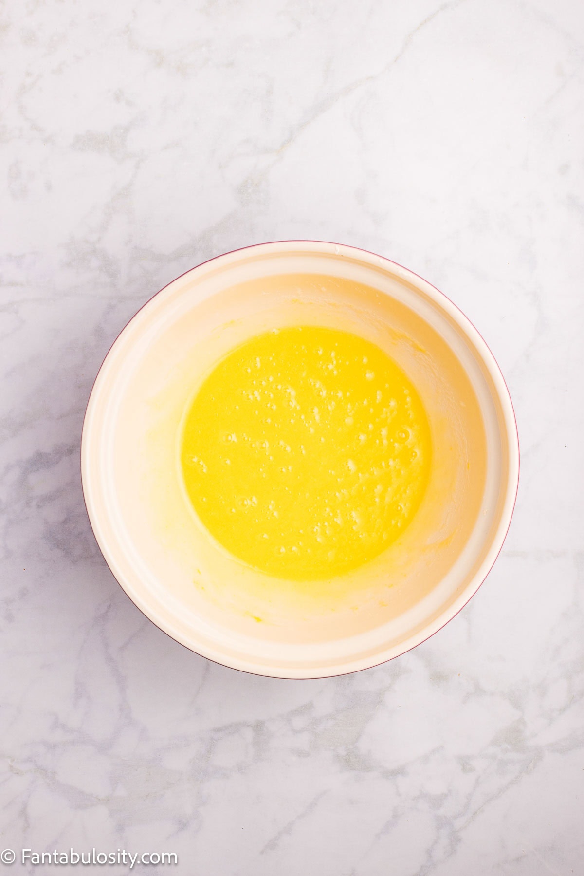 Eggs, sugar, and oil mixed together in mixing bowl for strawberry bread.
