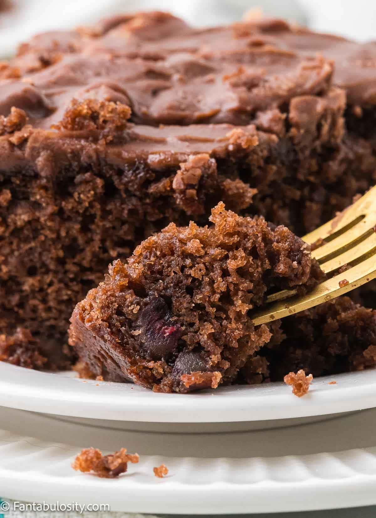 a slice of chocolate date Westhaven Cake on a plate, with a fork taking a bite off of the corner.
