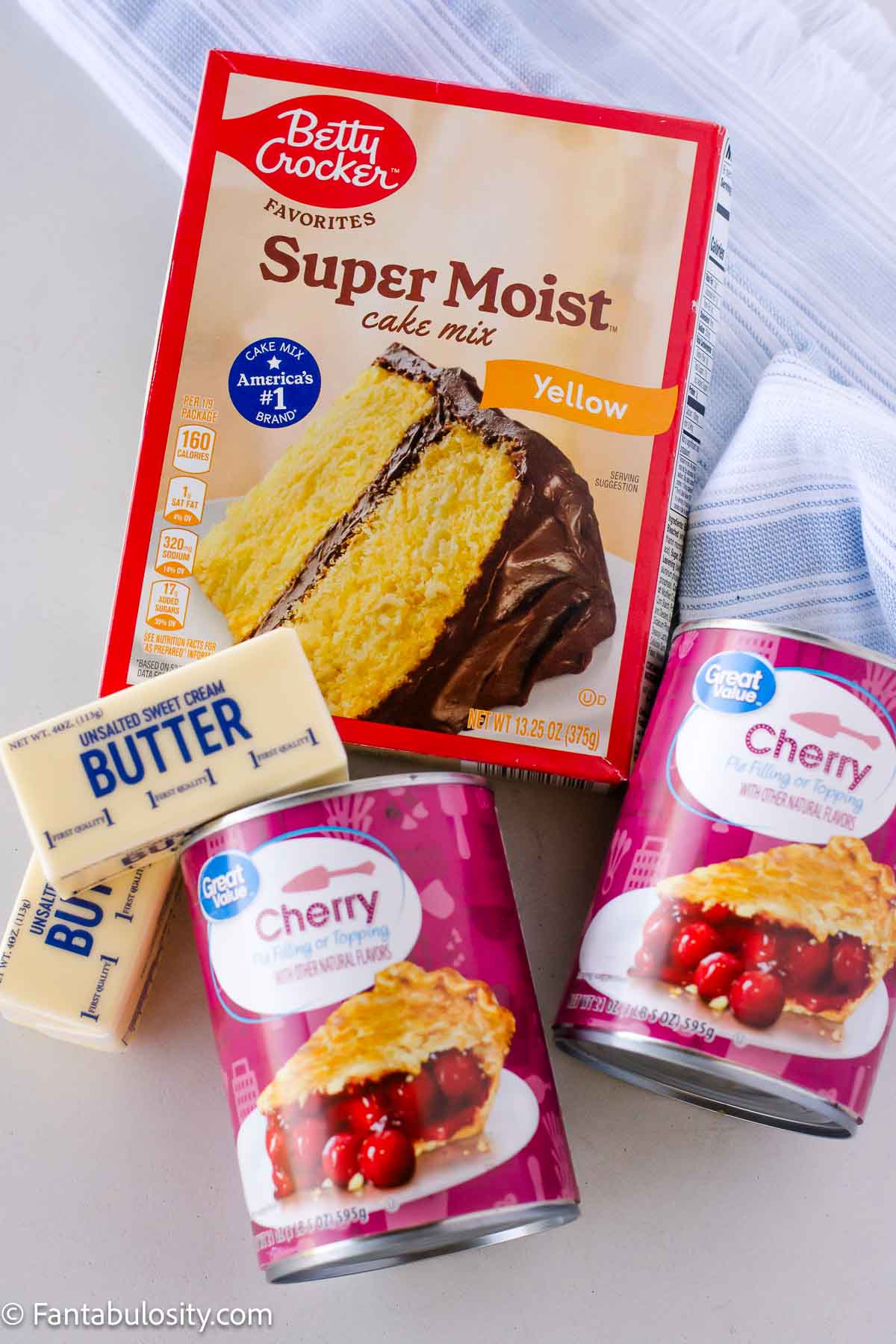 Ingredients to make a 3-ingredient dump cake, cake mix, canned pie filling and butter.