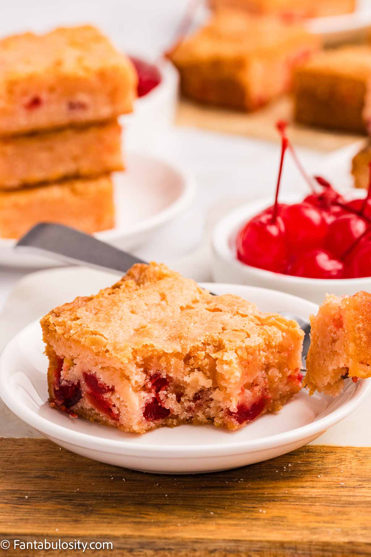 Cherry blondie on plate with fork taking a bite out of the corner.