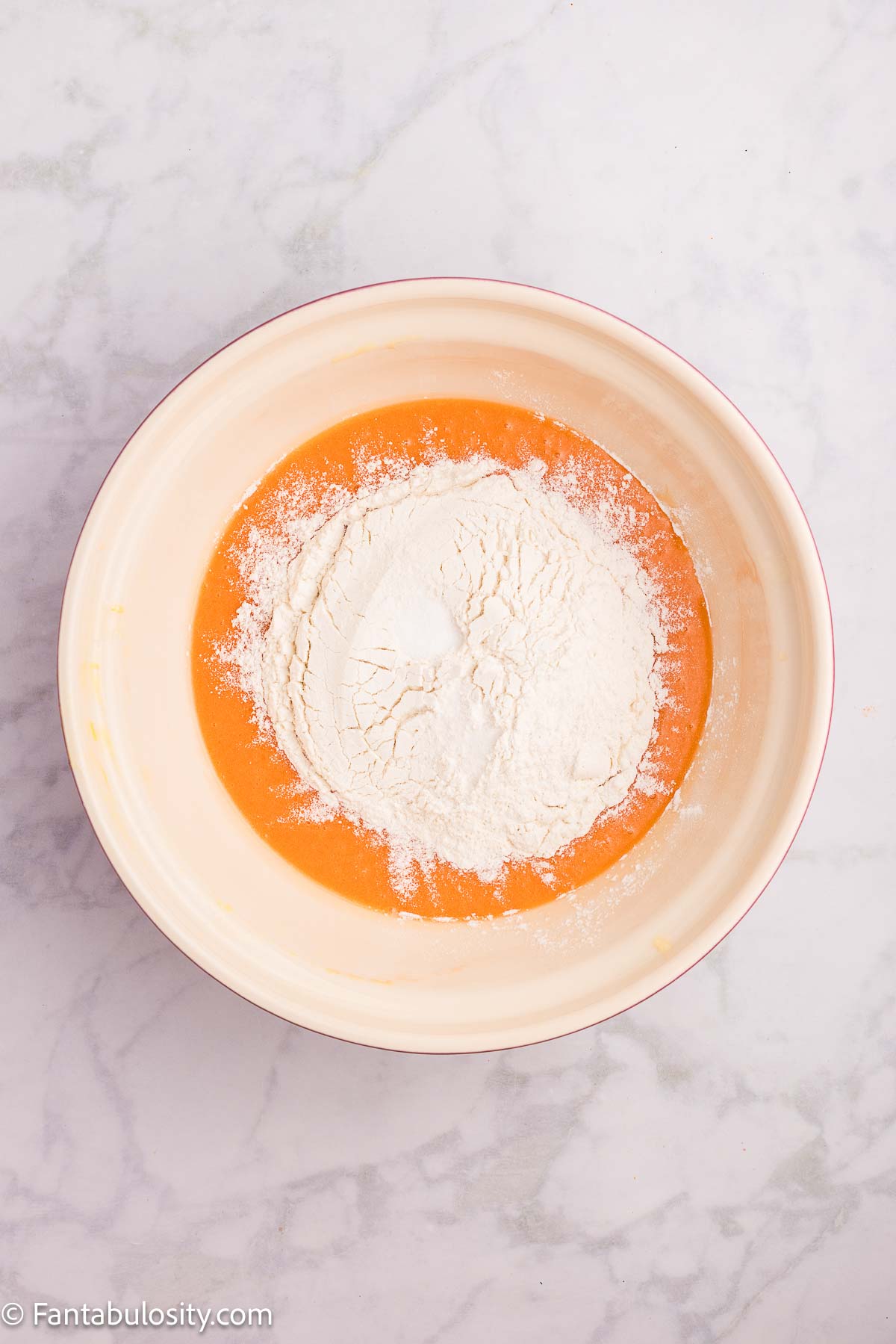 Flour added to sugar and butter mixture in mixing bowl.