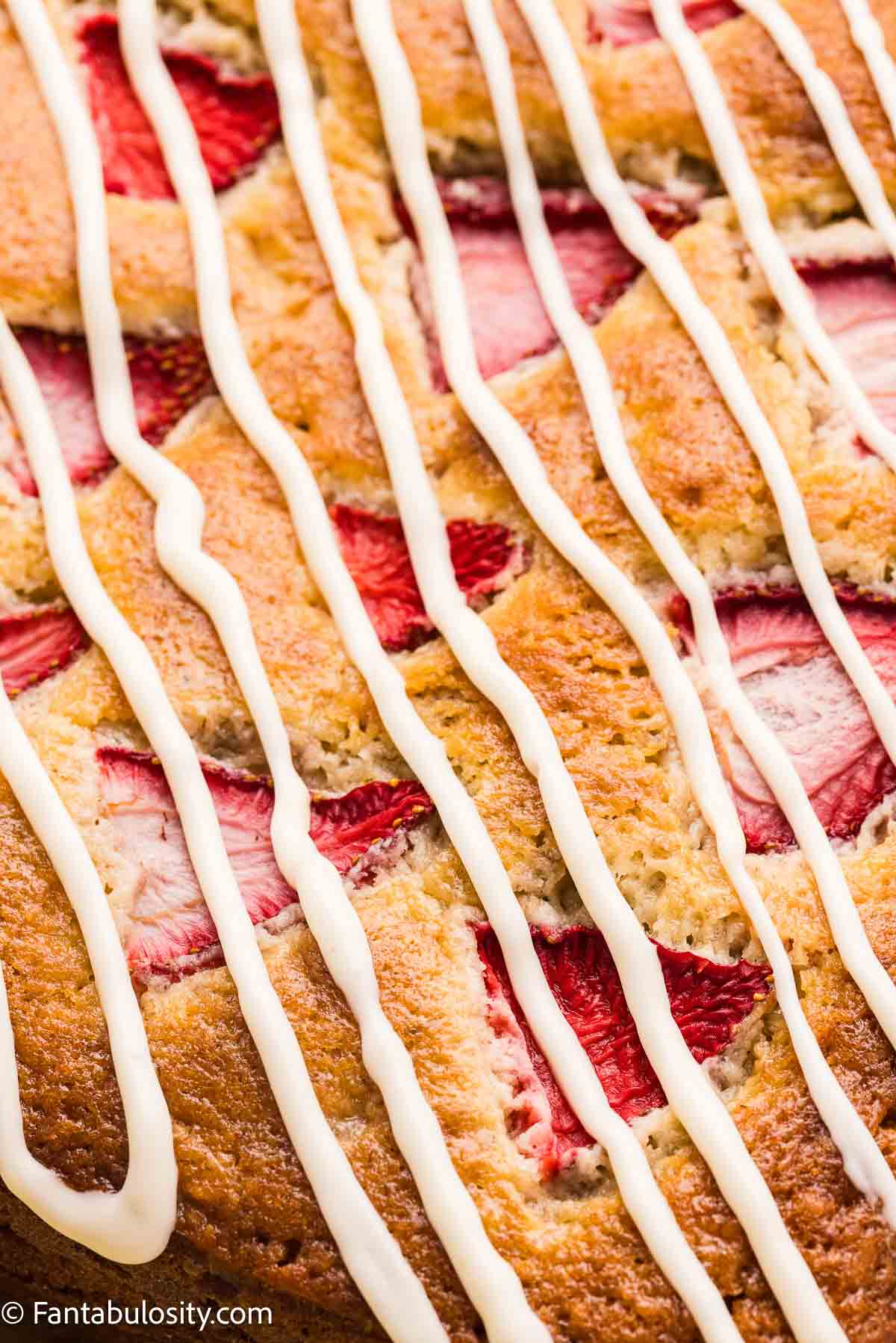 Cream cheese frosting drizzled on top of strawberry banana cake.