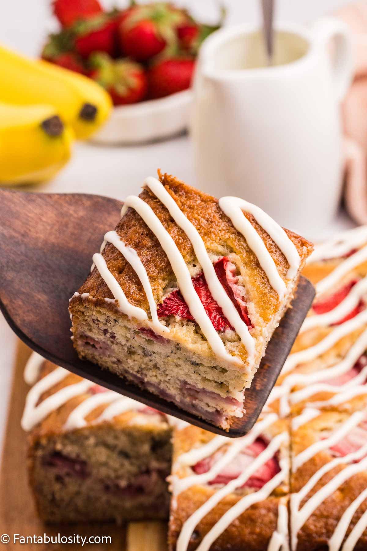 Slice of strawberry banana cake on a wooden spatula.