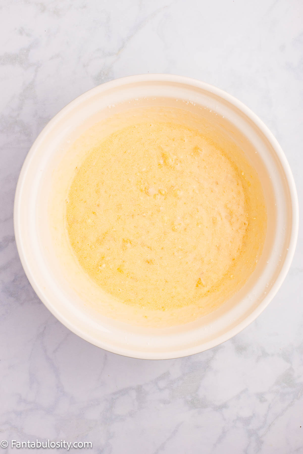 Mashed bananas and buttermilk added to cake batter in mixing bowl.