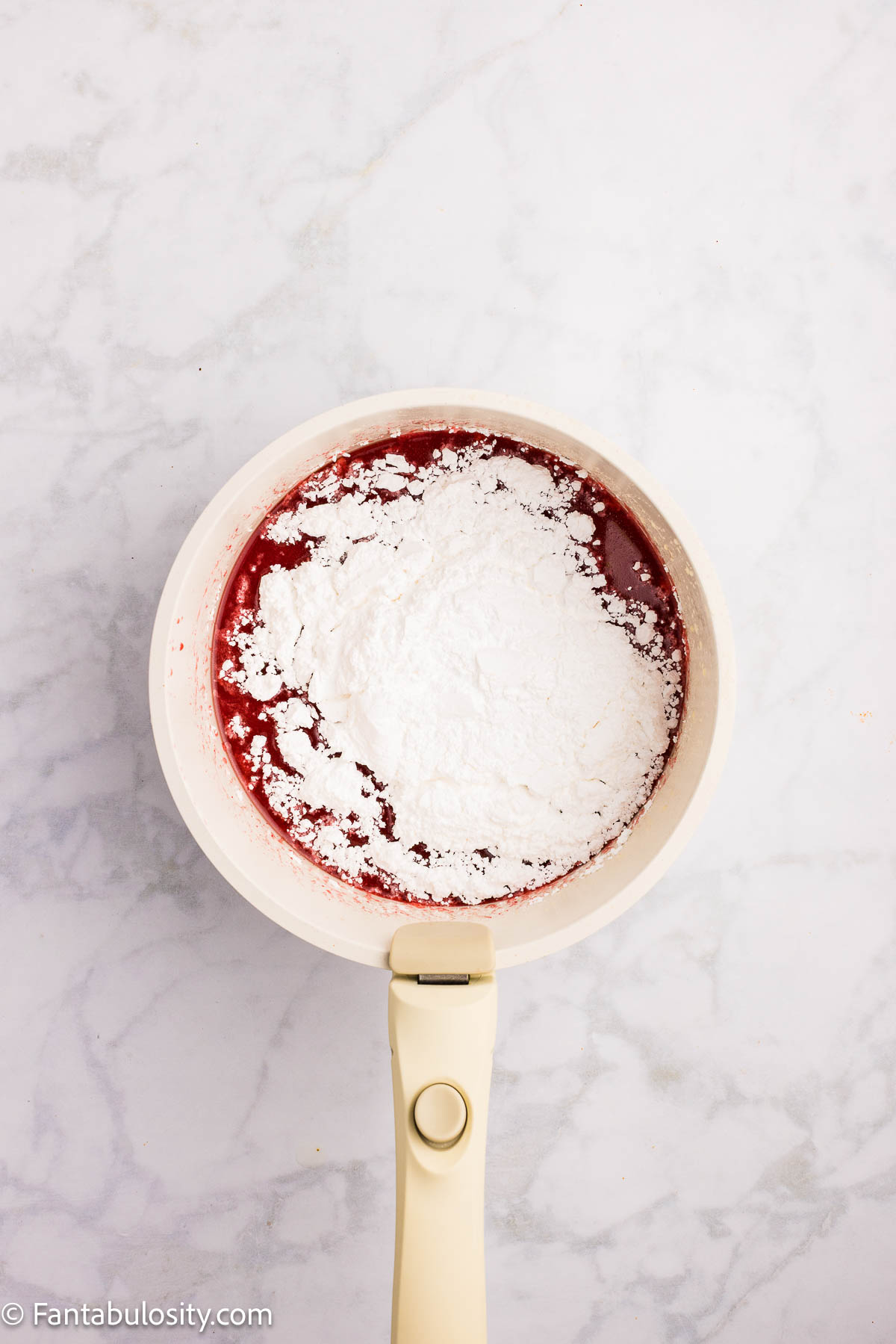 Powdered sugar added to saucepan for strawberry Texas sheet cake frosting.