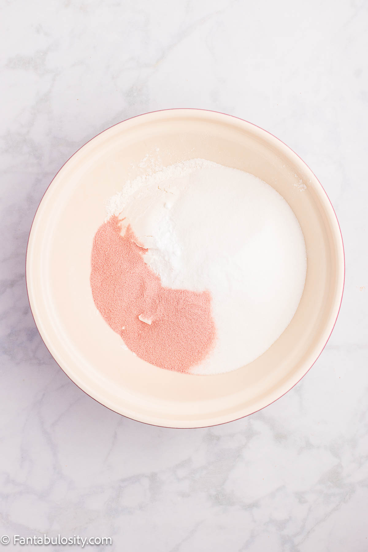 Dry ingredients, including strawberry jello mix, in mixing bowl.