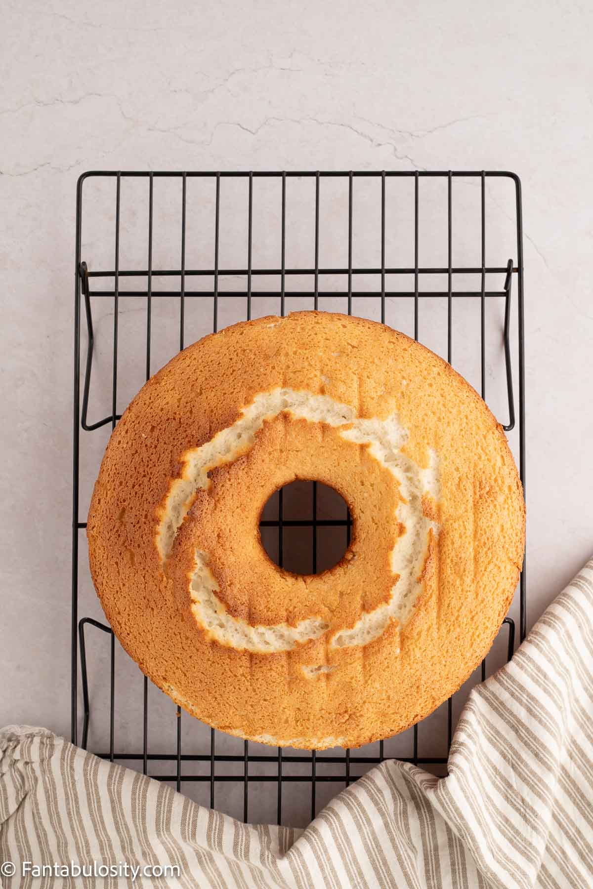Baked angel food cake cooling on wire rack.