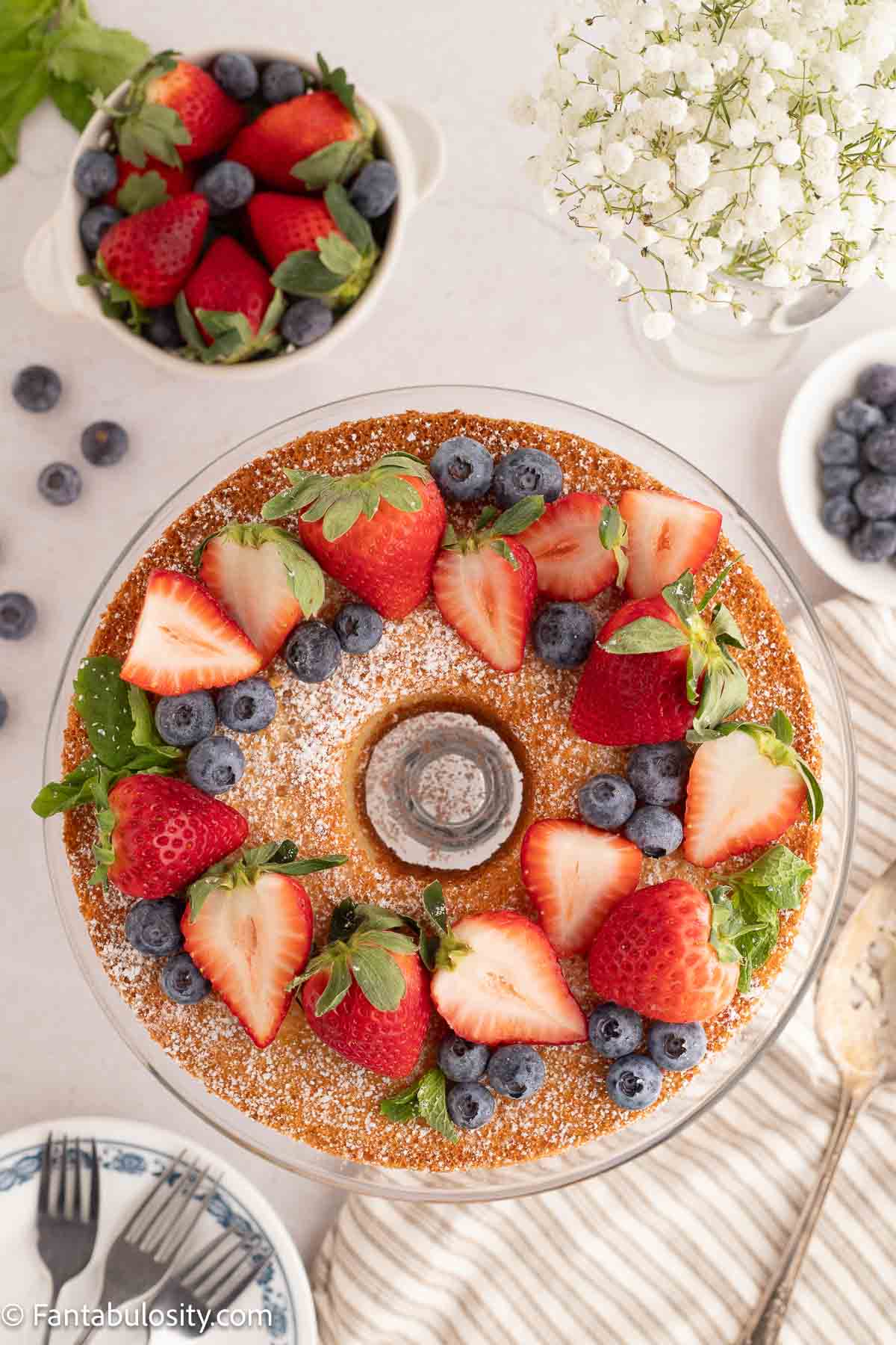 Powdered sugar sprinkled on top of angel food cake, as well as fruit.