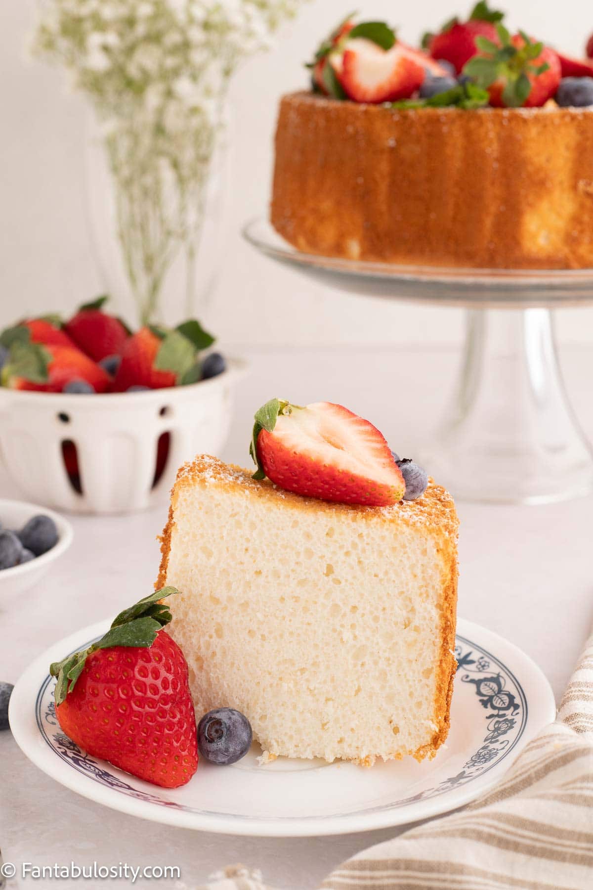 A slice of angel food cake on a plate, topped with strawberries.