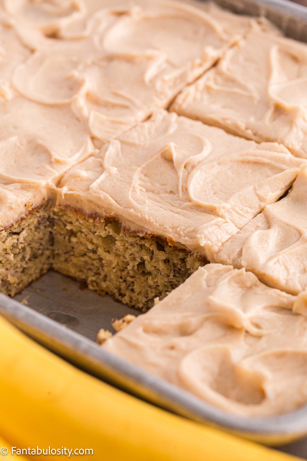 Banana cake with brown butter frosting sliced in 9x13 pan.