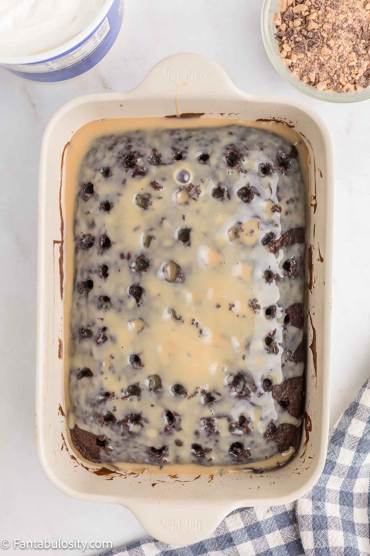 Caramel and condensed milk mixture poured over chocolate poke cake.