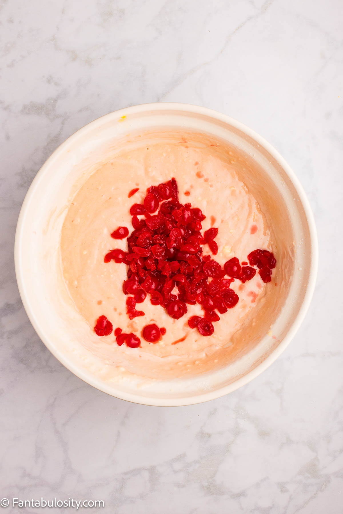 Cherries added to cherry cake batter in mixing bowl.