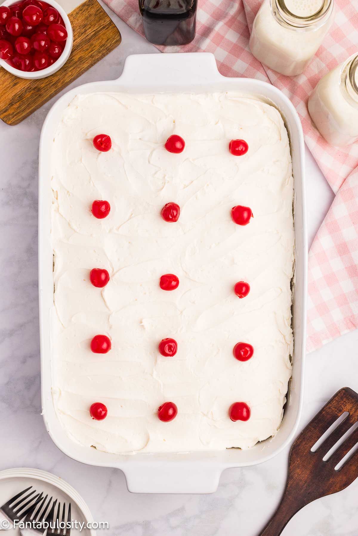 Cherry sheet cake frosted with icing and cherries.