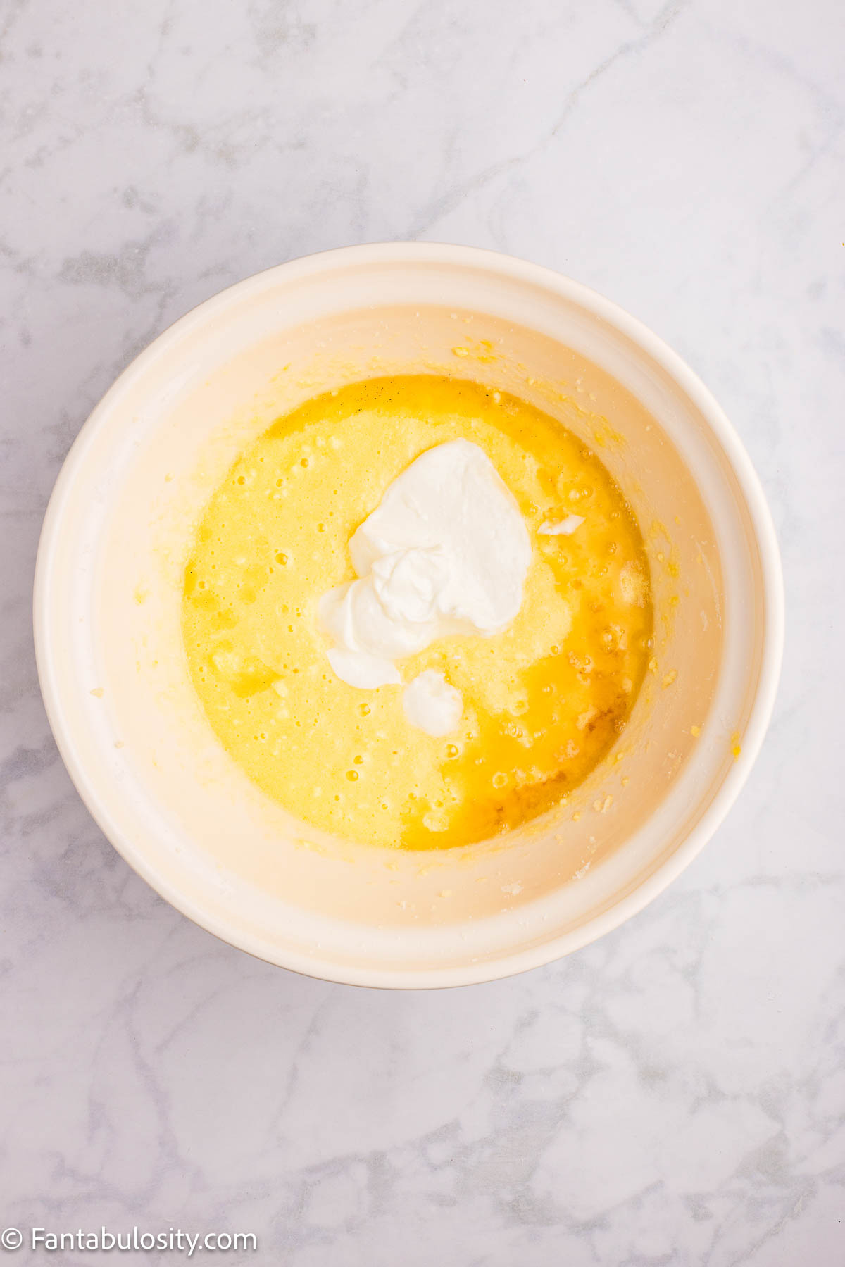 Greek yogurt added to sugar, egg and butter mixture in mixing bowl.