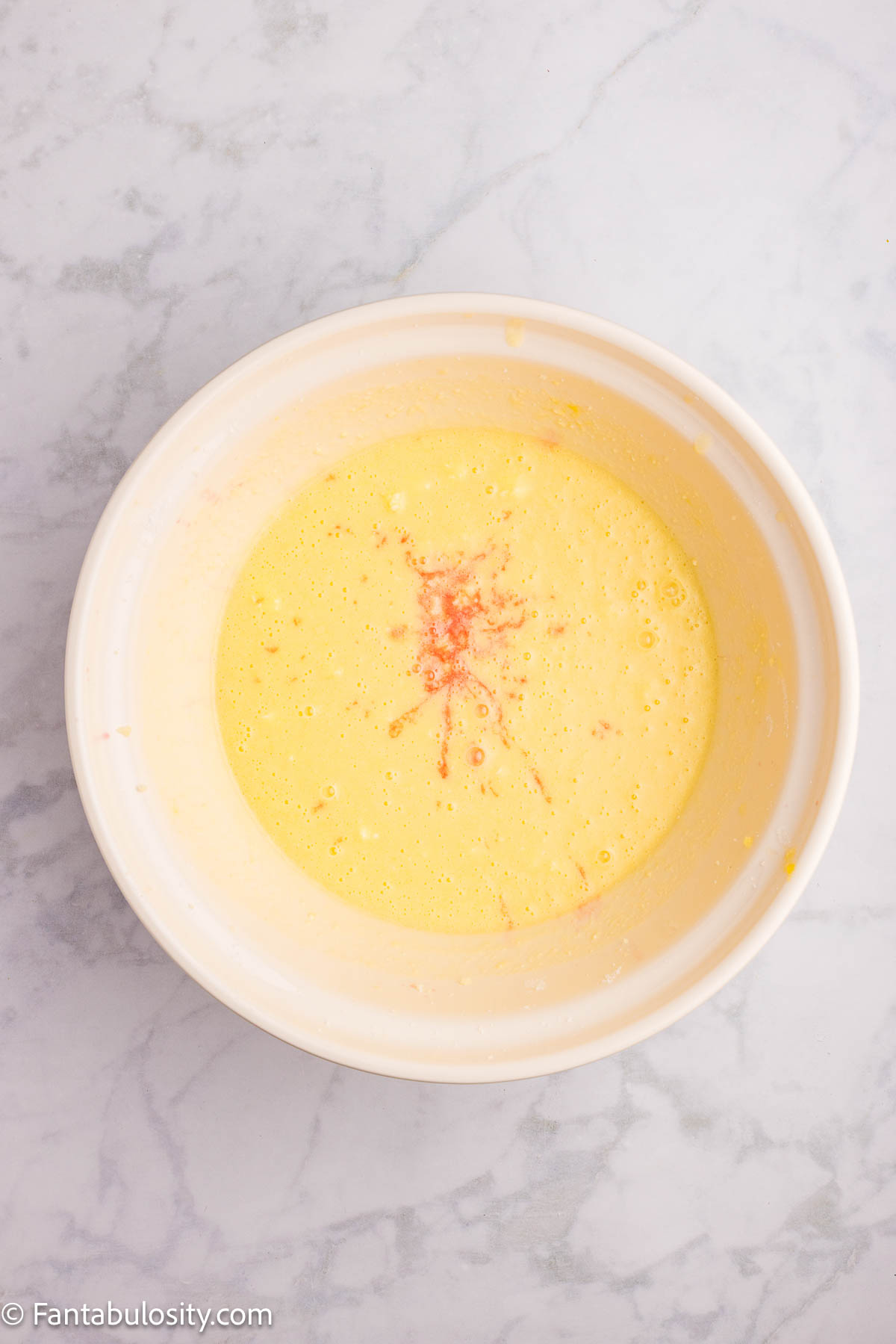 Cherry juice added to cake batter in mixing bowl.