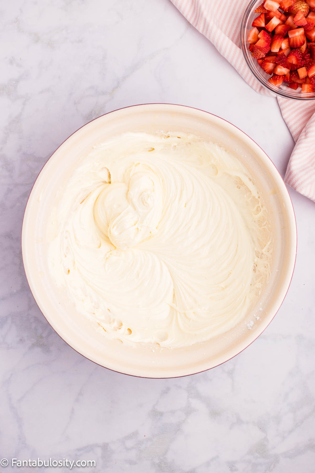 Cream cheese mixture in mixing bowl for the strawberry earthquake cake.