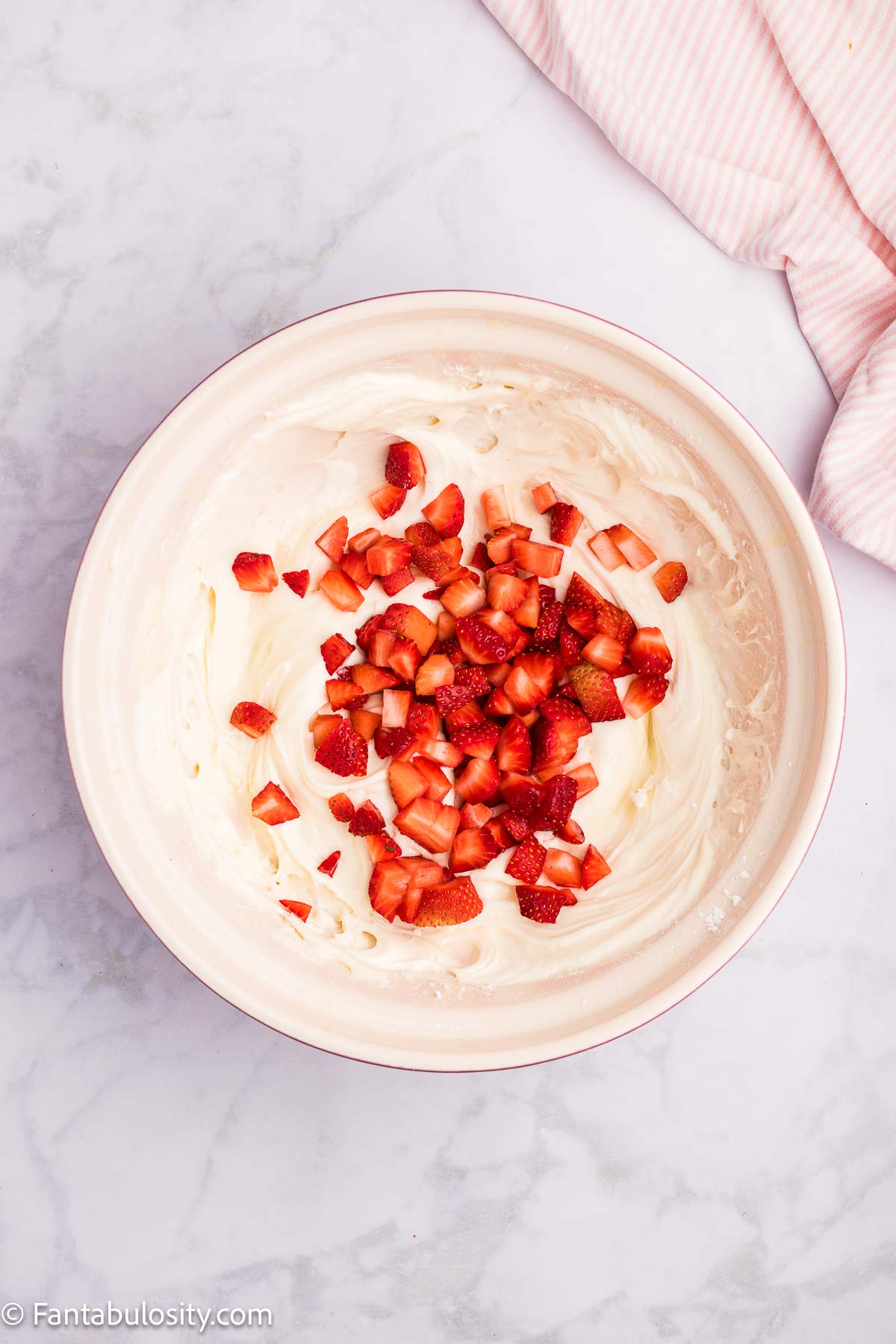 Strawberries added to cream cheese mixture in mixing bowl.