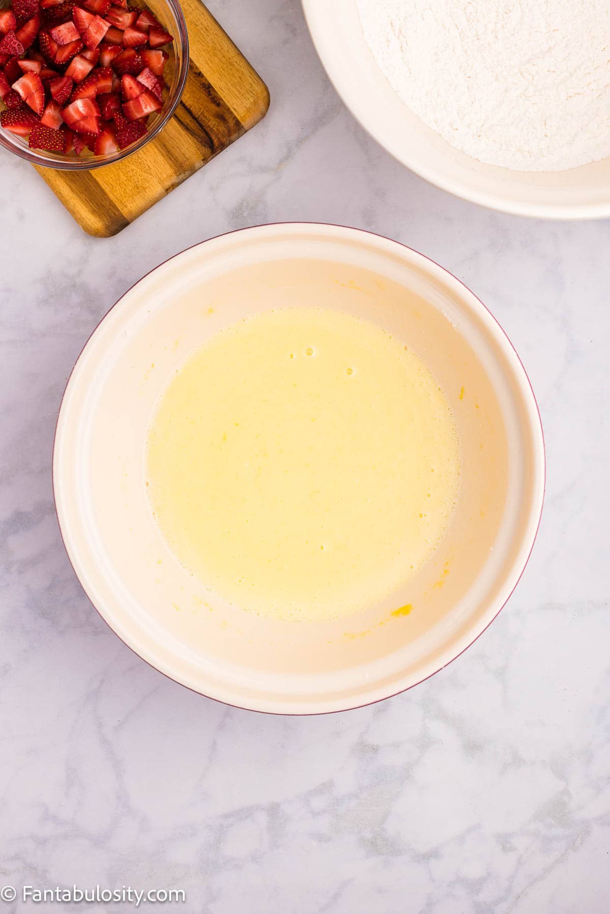 Yogurt, oil, eggs, and lemon juice mixed in a bowl.