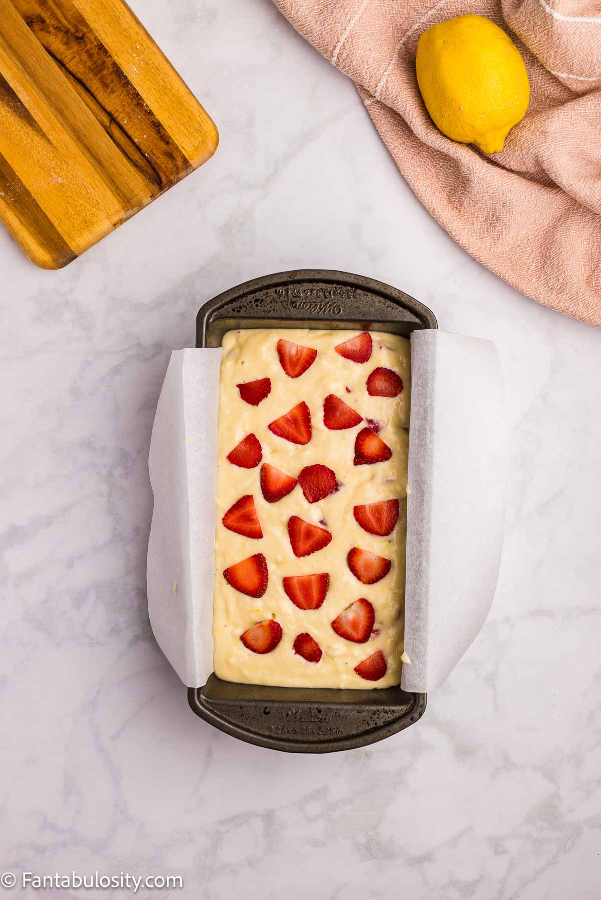 Strawberries placed on top of bread in loaf pan.